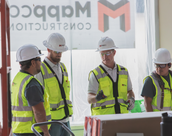 Construction workers standing over architectural plans